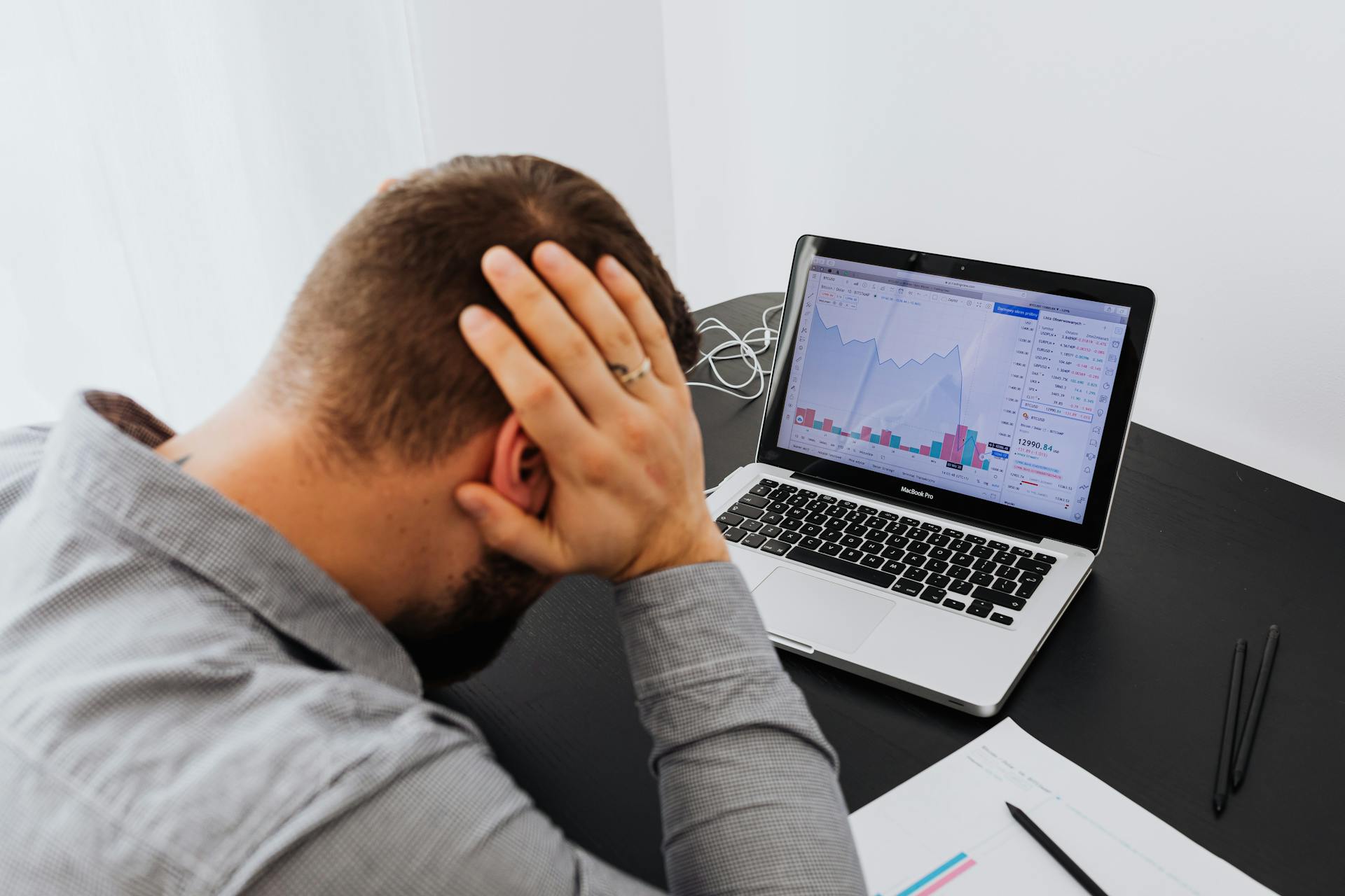 Trader assis devant son ecran, decourage par les pertes successives